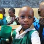 African schoolgirl surrounded by classmates eating a nutritious lunch