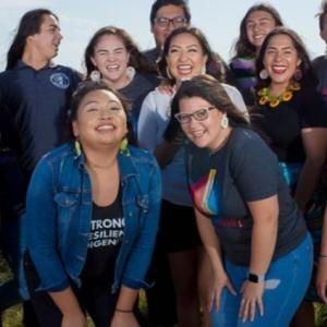 A group of 8 young indigenous women smiling and laughing for the camera.